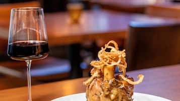 Una mesa de comedor con un plato de comida y una copa de vino tinto.