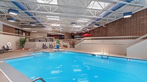 Une piscine intérieure à l’eau d’un bleu limpide, entourée d’un mur de briques et d’une rambarde blanche.