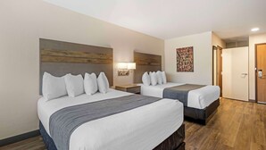 Une chambre d’hôtel avec deux lits, une tête de lit en bois, une lampe fixée au mur et une porte dotée d’un système de verrouillage à clavier.