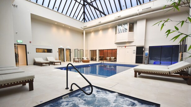 Amplia zona de piscina interior con sillones de descanso y jacuzzi.