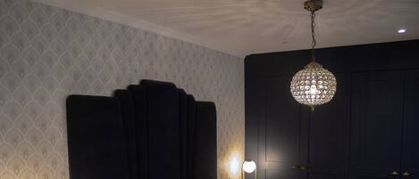 Camera d'albergo con un grande letto, lampade sui comodini, un armadio e una lampada a sospensione.