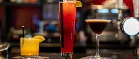 Three cocktails on a bar counter with a blurred background.