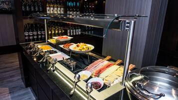 A buffet with various food items and a selection of wine bottles.