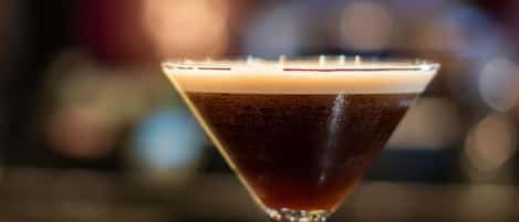 A martini glass with a dark liquid on a bar counter.