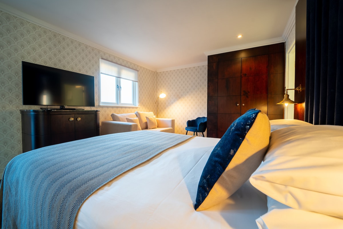 Ein Hotelzimmer mit einem großen Bett, einem Flachbildfernseher, einem Schreibtisch und einem Kleiderschrank.