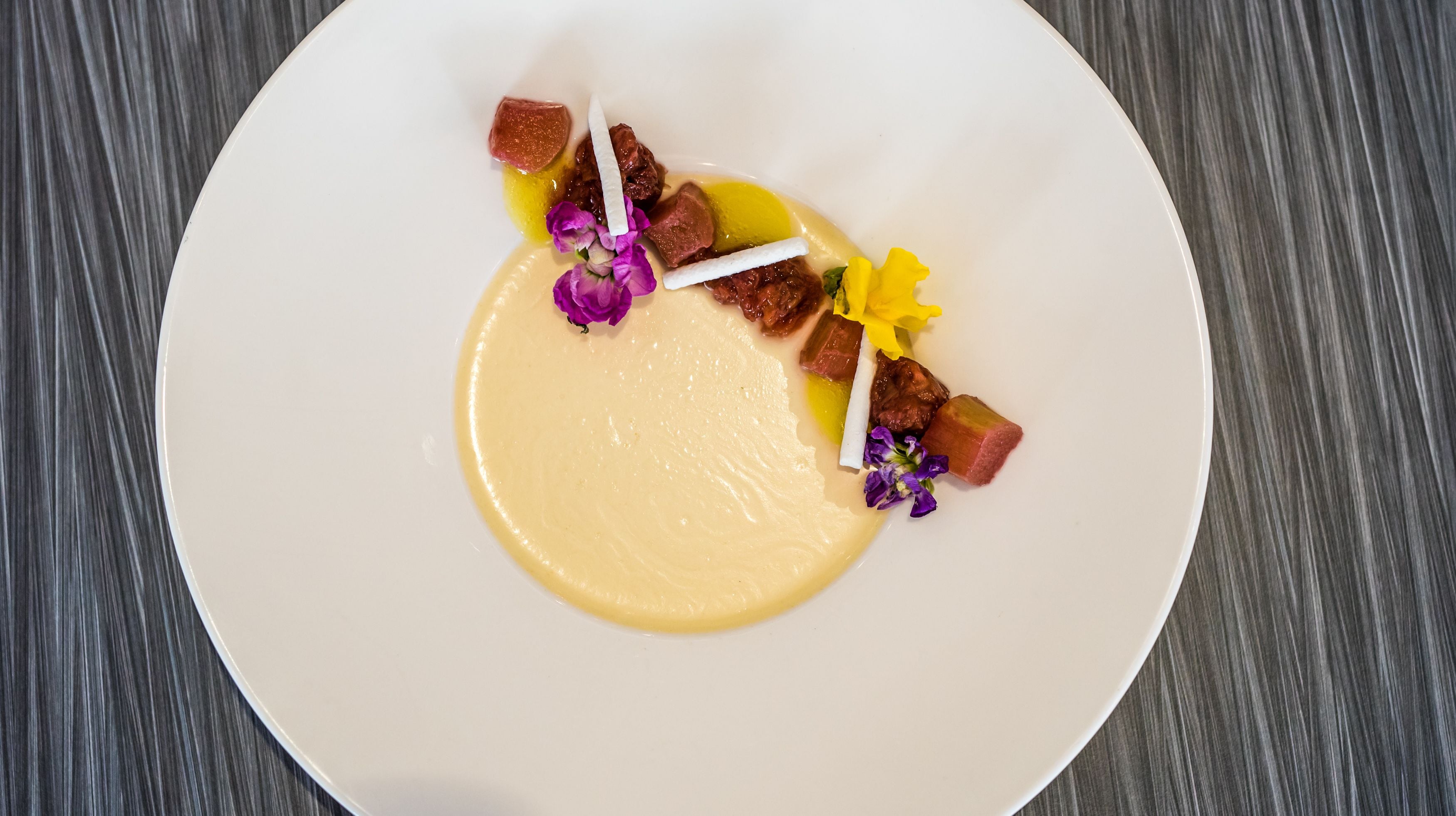 A white plate with a creamy sauce, small cubes of meat, and decorative flowers.