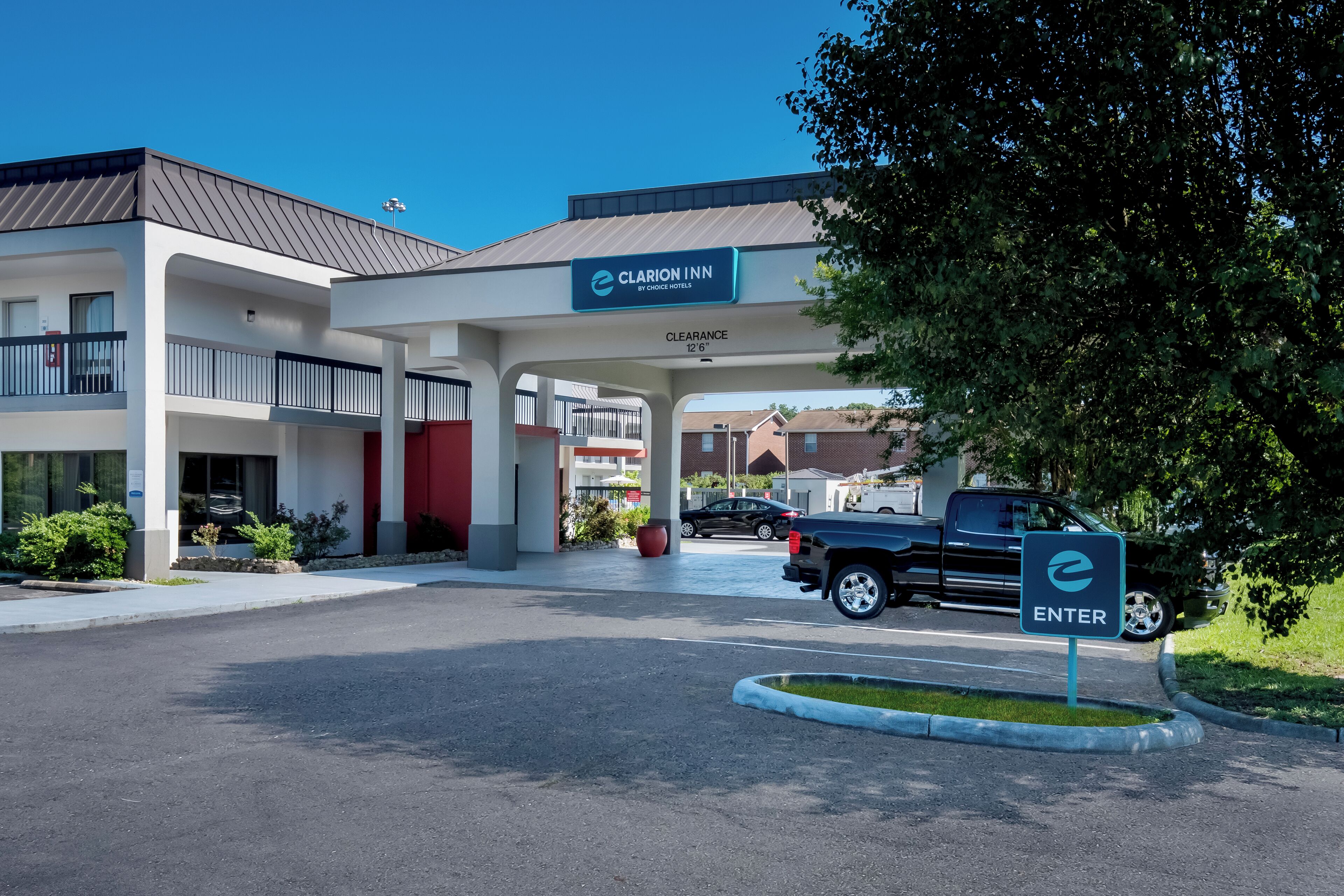 A Clarion Inn by Choice Hotels with a clear entrance, a parking area, and a sign indicating the entrance.