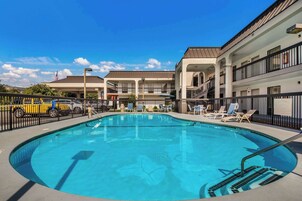 Una piscina al aire libre de temporada, sombrillas, tumbonas