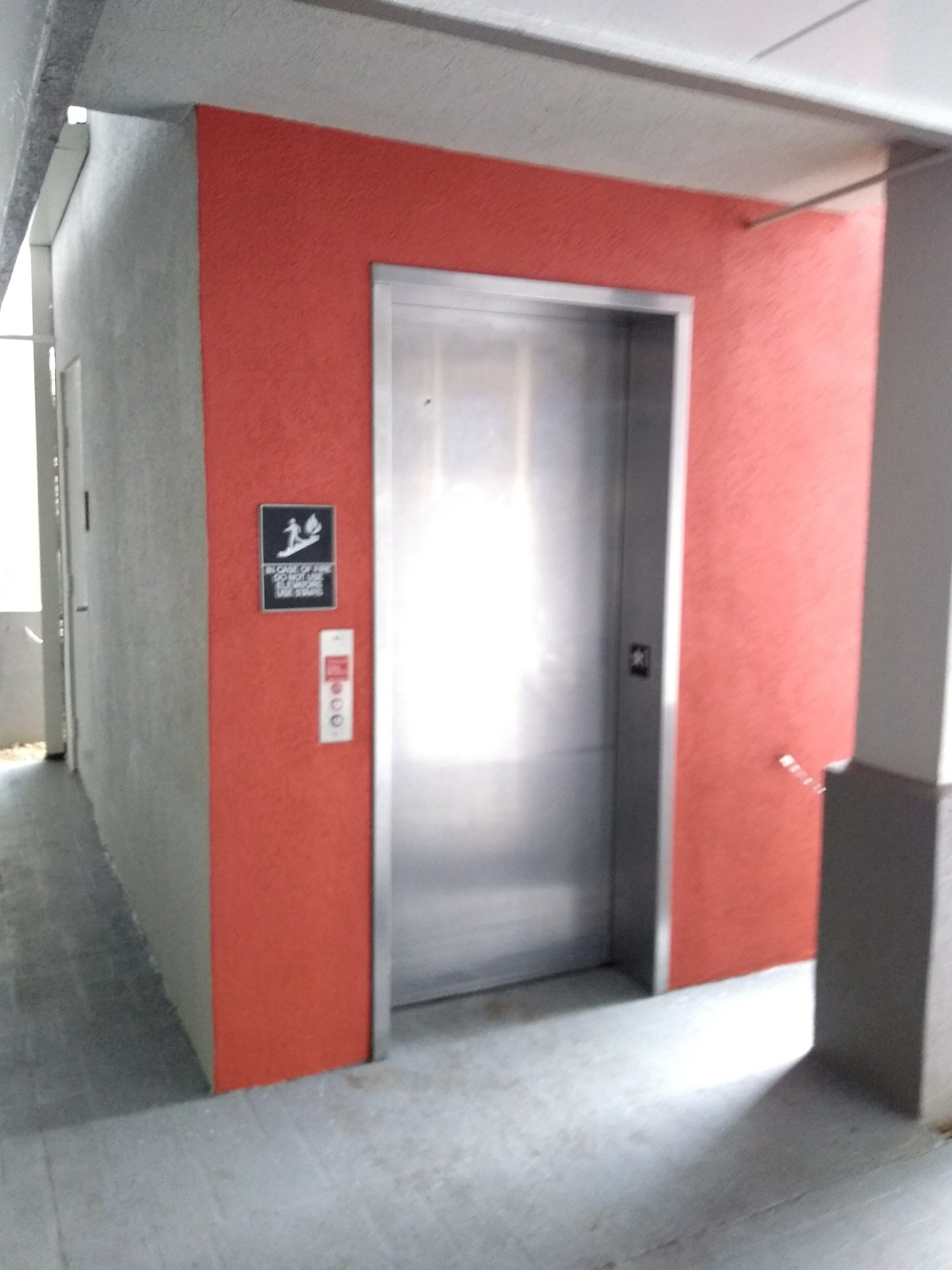 An elevator in a hallway with a red wall and a sign indicating it is a lift.