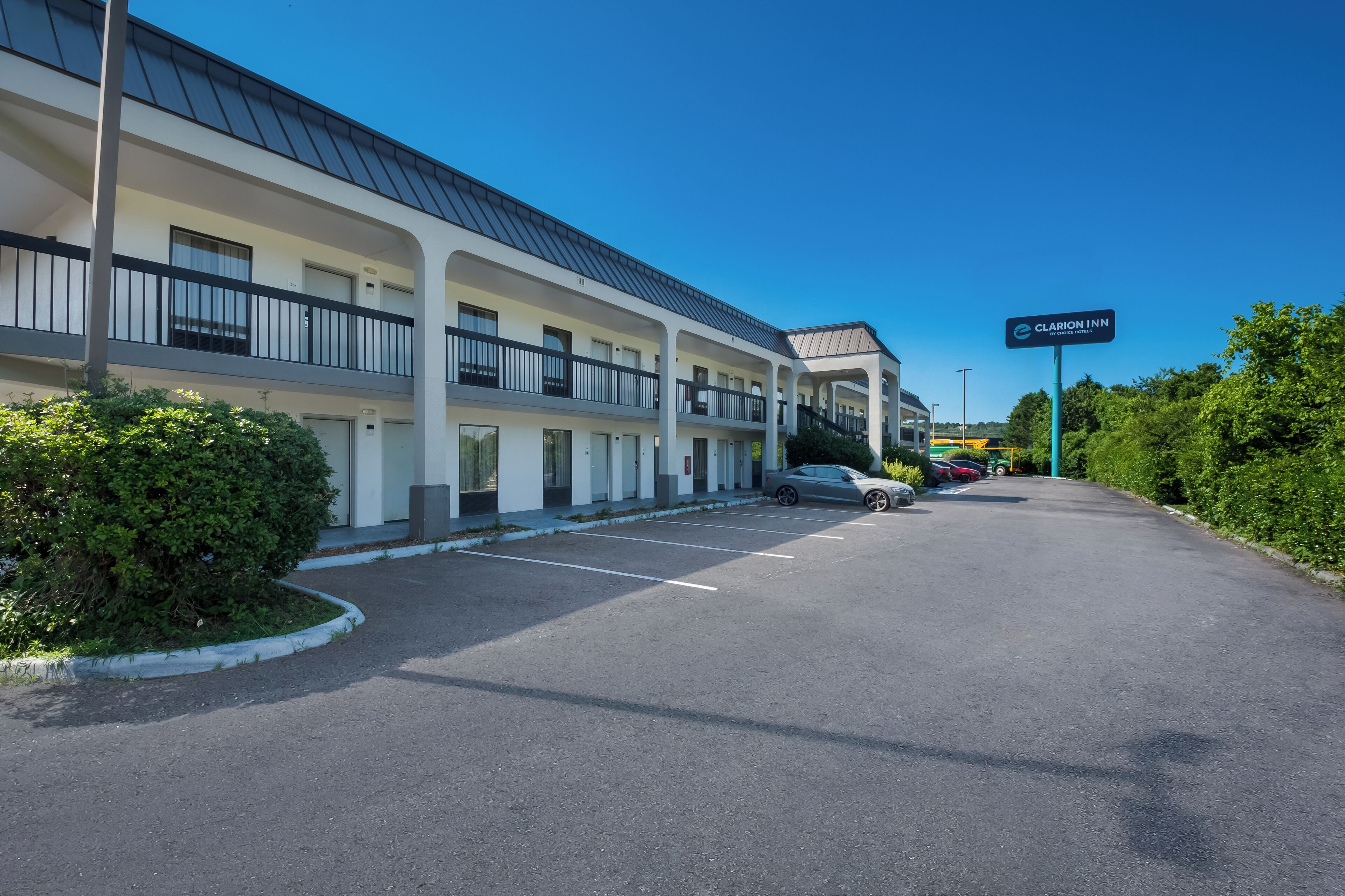 A multi-story motel with a parking lot, a sign for Clarion Inn, and a clear blue sky.