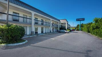 A multi-story motel with a parking lot, a sign for Clarion Inn, and a clear blue sky.