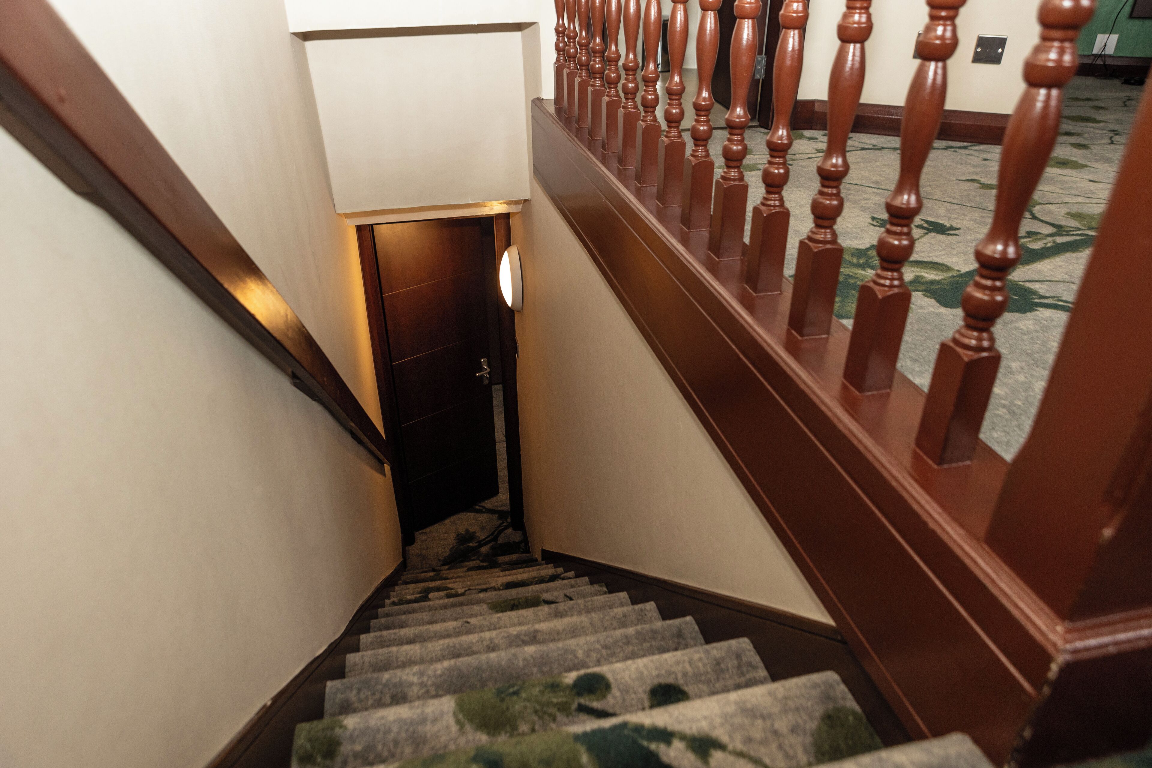 Una scala tappezzata con balaustre in legno che conduce a una porta.