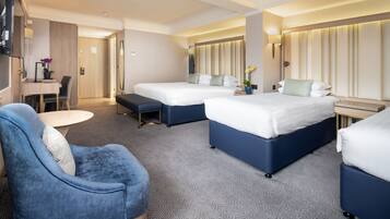 Une chambre d’hôtel avec deux lits, un bureau, une chaise et une télévision.