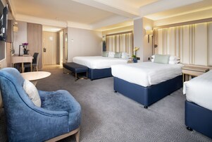 Une chambre d’hôtel avec deux lits, un bureau, une chaise et une télévision.