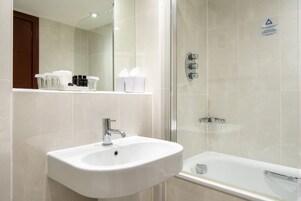 Ein modernes Badezimmer mit einem weißen Waschbecken, einer Duschkabine und einem Spiegel über dem Waschbecken.