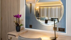 A modern bathroom with a round mirror, a potted orchid, and a wooden vanity. - Danubius Hotel Regents Park (London)