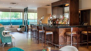 A bar area with stools, a bar counter, and a view of the outdoors. - Danubius Hotel Regents Park (London)