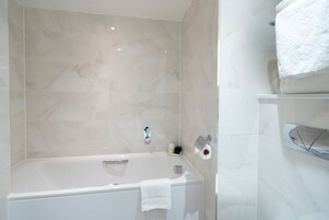 Ein modernes Badezimmer mit einer Badewanne, einer Toilette und einem Ablagebereich mit einem Handtuch.