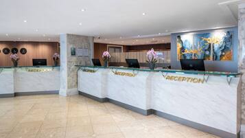A reception area with marble counters, a flat-screen TV, and potted orchids.