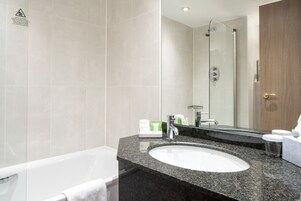 A bathroom with a white sink, a glass shower enclosure, and a wooden door.