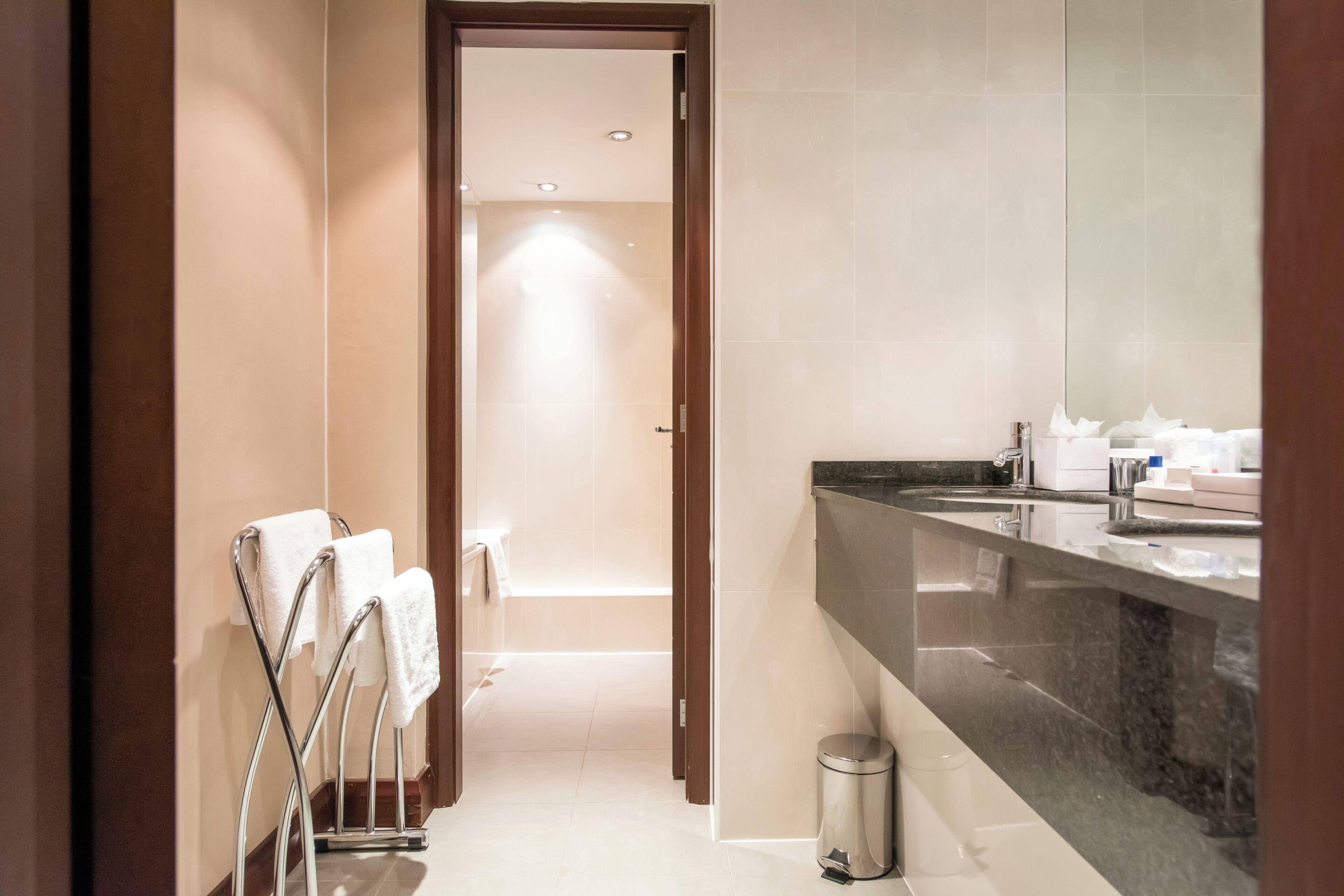 A modern bathroom with a large mirror, a sink, and a towel rack.