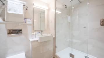 A modern bathroom with a glass-enclosed shower, a white sink, and a mirror above it.