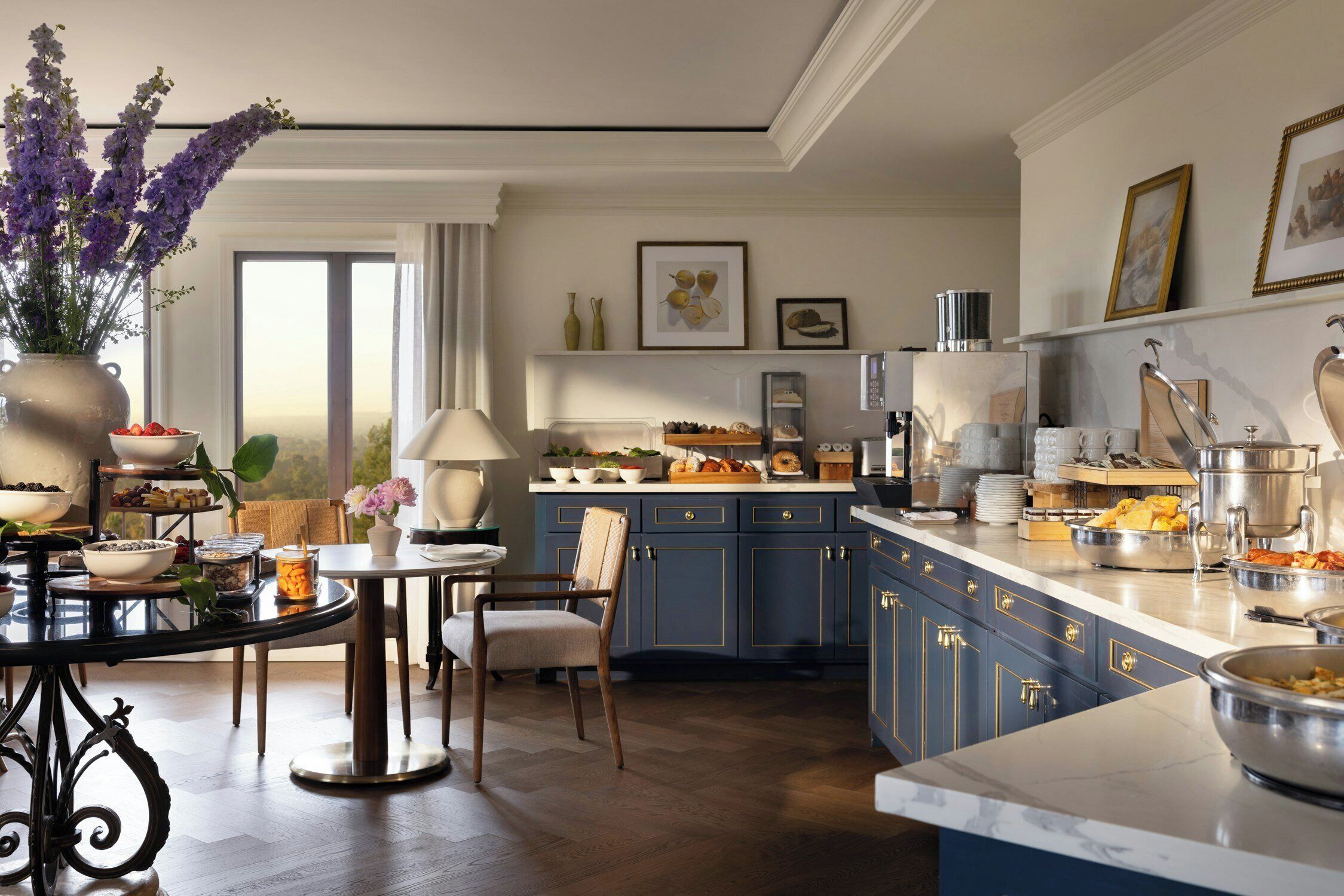 A modern kitchen with blue cabinets, a marble countertop, and a dining area with a round table and chairs.