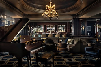 A grand lobby with a chandelier, a round table with a vase of flowers, and two armchairs. at Langham Huntington, Pasadena, Los Angeles
