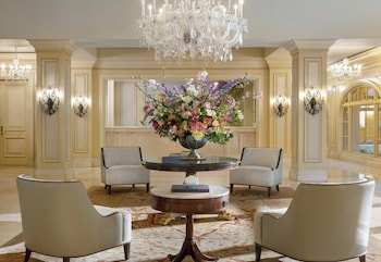 A spacious, elegantly furnished room with a grand piano, multiple seating arrangements, and large windows offering a view of greenery. at Langham Huntington, Pasadena, Los Angeles