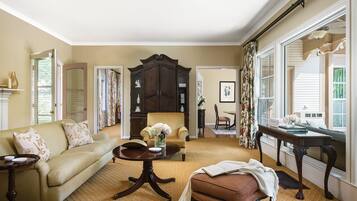 A spacious living room with a sofa, armchair, and a dining table.