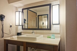 Un bagno d'hotel con uno specchio grande, un lavandino e un asciugacapelli a parete.