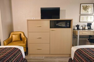 Una camera d'albergo con un letto, un divano, una scrivania con forno a microonde e una televisione sopra un mobile.