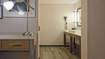 Un baño de hotel con un tocador de madera, un lavabo, un espejo y un teléfono.