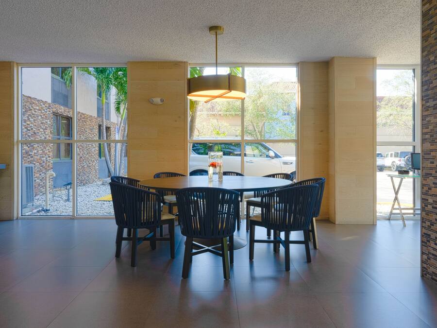 Un comedor amplio con una mesa grande y sillas, una lámpara colgante y ventanas grandes que ofrecen vistas al exterior.