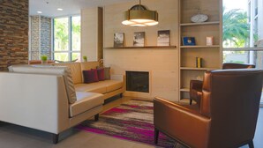 Un salon moderne comprenant un canapé, des fauteuils, une cheminée et une bibliothèque.