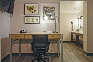 Une chambre d’hôtel équipée d’un bureau, d’une chaise et d’une œuvre d’art au mur.