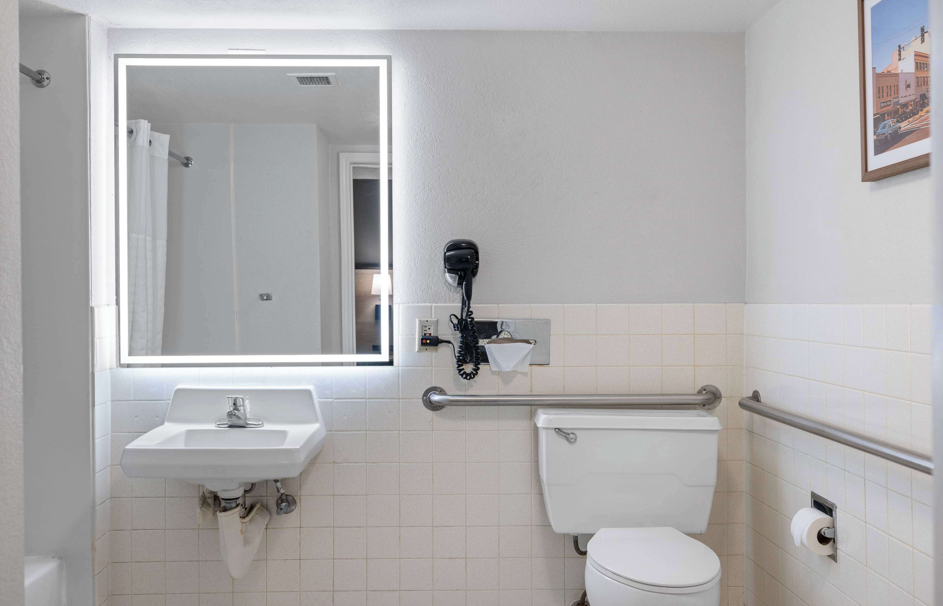 A bathroom with a sink, toilet, and a mirror.