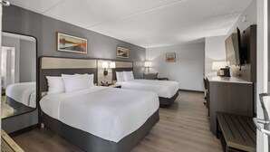 Una habitación de hotel con dos camas, un escritorio, un espejo y obras de arte en las paredes.