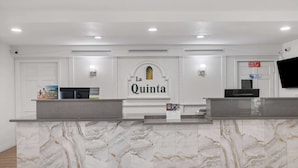 Un mostrador de recepción con diseño de mármol, un letrero que dice "La Quinta" y una pantalla de televisión.