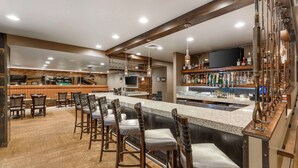 A bar area with a long counter, multiple stools, and a variety of bottles and glasses on shelves. - Best Western CottonTree Inn (Rawlins)