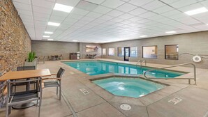 An indoor swimming pool with a stone wall, poolside seating, and a tiled ceiling. - Best Western CottonTree Inn (Rawlins)