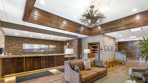 A modern lobby with a reception desk, wooden flooring, a leather sofa, and a chandelier. - Best Western CottonTree Inn (Rawlins)