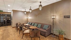 A lobby with a sofa, chairs, a table, and a floor lamp. There is a sign indicating a fitness room and lounge. - Best Western CottonTree Inn (Rawlins)