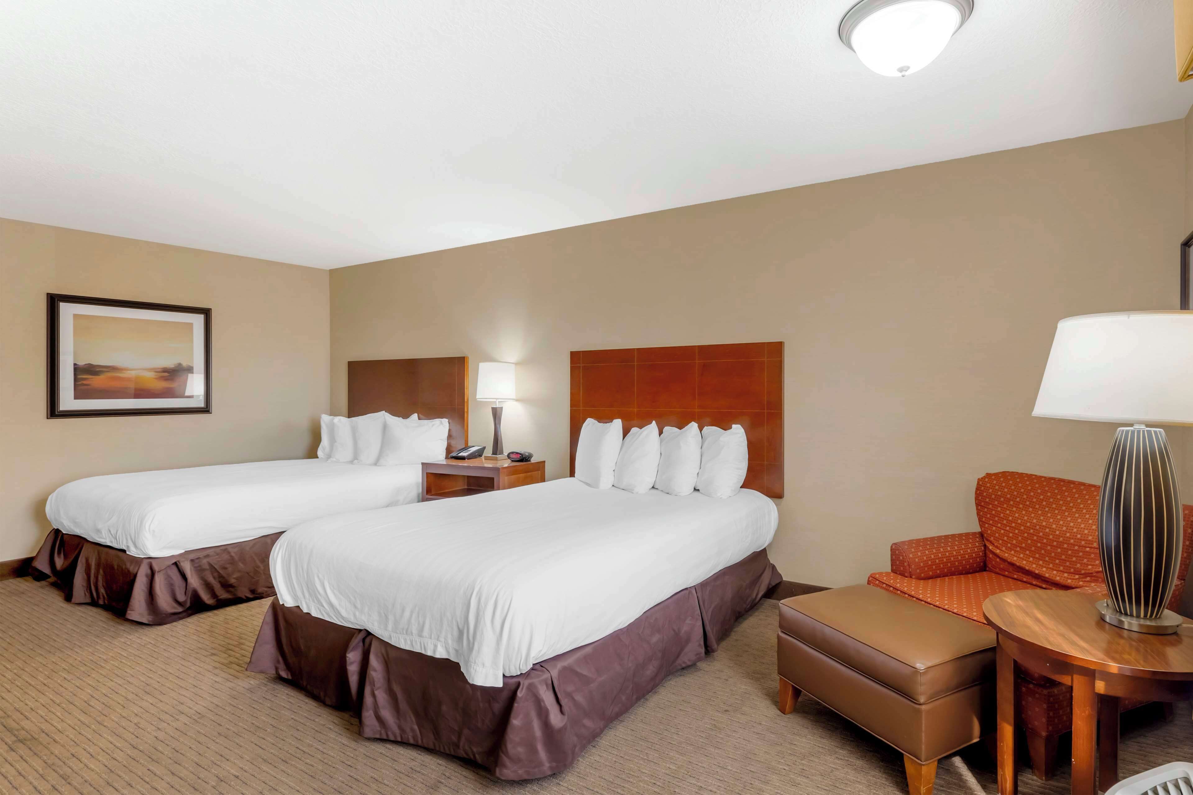 A hotel room with two beds, a sofa, a small table, and a lamp.