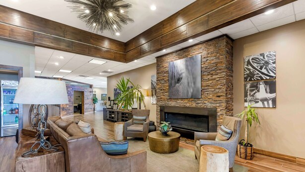 A spacious lobby with a fireplace, leather sofas, and a modern chandelier. - Best Western CottonTree Inn (Rawlins)