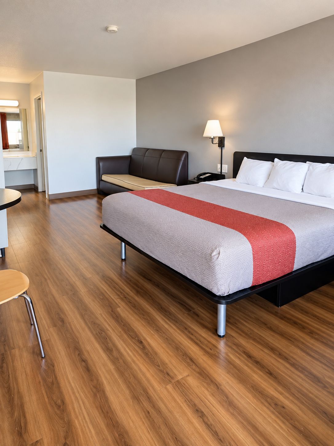 A hotel room with a bed, a desk, a chair, and a nightstand.