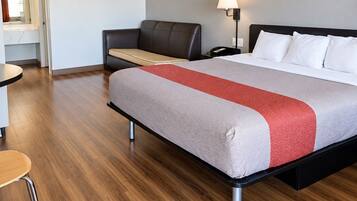 A hotel room with a bed, a desk, a chair, and a nightstand.