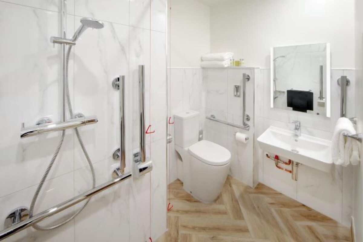 Een moderne badkamer met douche, toilet en wastafel.