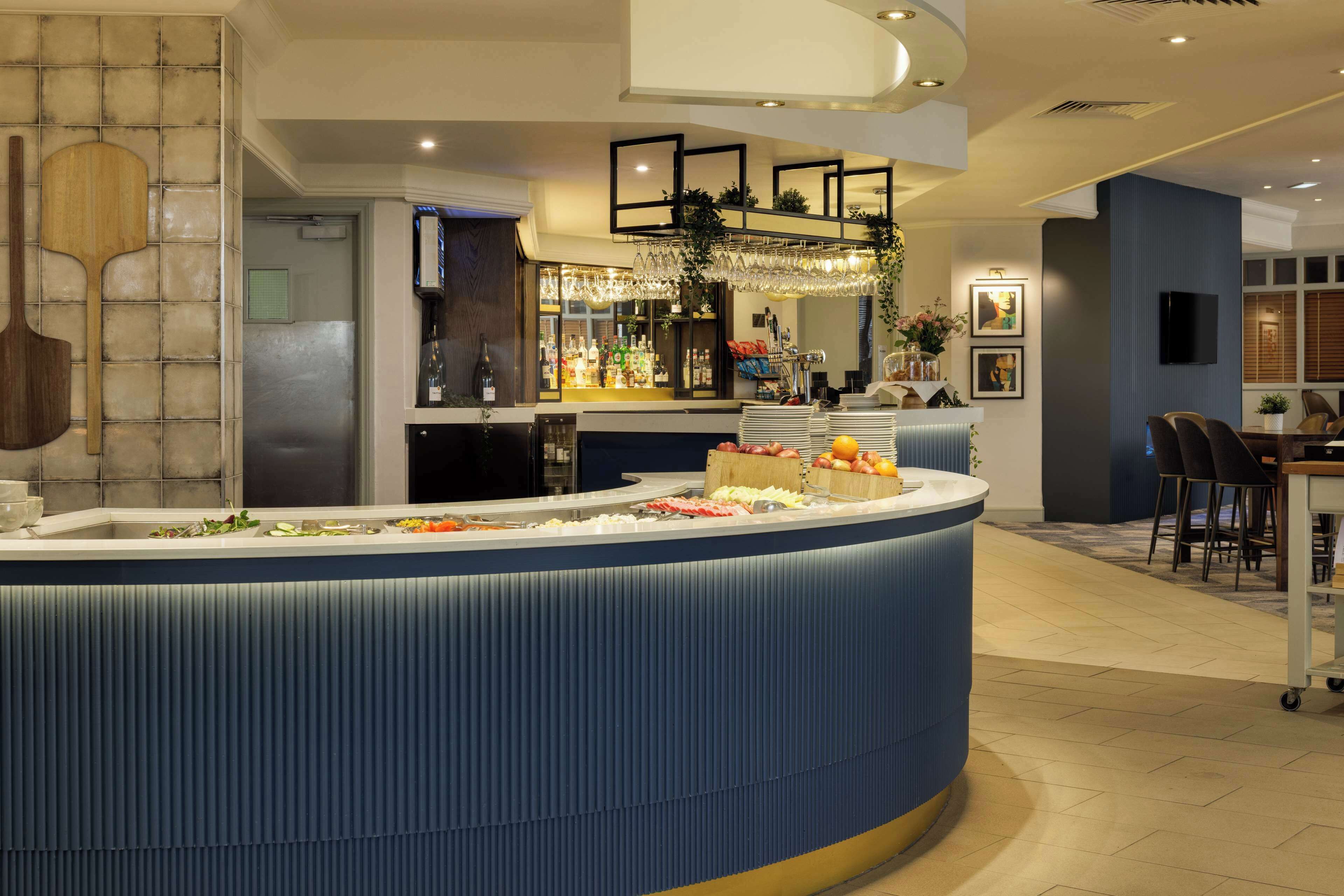 A hotel lobby with a curved reception desk, a bar area, and seating.