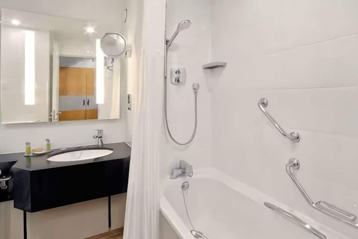 A modern bathroom with a white sink, mirror, and shower area.